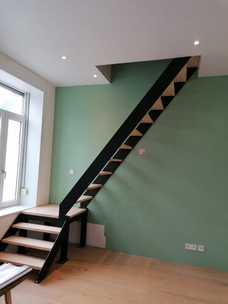 Une pièce avec un mur vert vibrant et un élégant escalier en bois, contribuant à un environnement frais et accueillant.