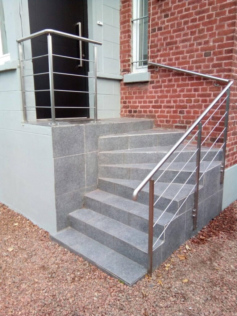 Un escalier moderne avec garde-corps et marches en métal, conçu pour la sécurité et l'élégance dans les espaces résidentiels et commerciaux.